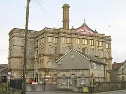 Four storey building with chimney behind gates and walls.