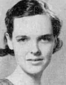 A young white woman with short dark hair in curls behind her ears.