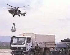 A helicopter arrives at a refugee facility in Macedonia with an underslung load of Aid