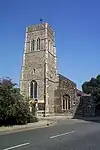 A tall flint tower with the body of the church extending beyond it