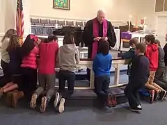 A Methodist Pastor distributing ashes to confirmands kneeling at the chancel rails, 2016