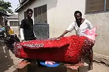 Ataa Oko and Kudjo Affutu with Oko's red rooster coffin for Regula Tschumi (2009)