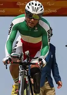 Male cyclist in the Uniform of the Iranian Paralympic Team riding a bicycle