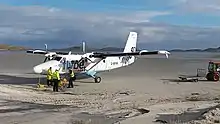 Twin Otter at Barra airport, ground crew preparing for takeoff