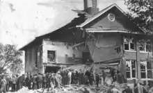 onlookers mill around, looking at the half-destroyed Bath School building