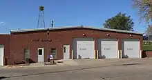 One-story brick building with garage-type doors; siren on tower behind it