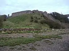 A ruined stone wall on a grassy knoll