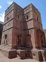 A picture of a pick-coloured building intact inside of a large, square hole