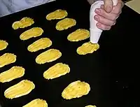 Piping out the dough for beignets with a pastry bag