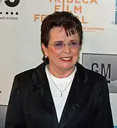 A brown haired women in a black jacket and white shirt