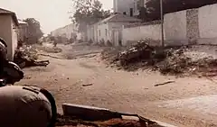 Sandy city street, soldier barely in foreground