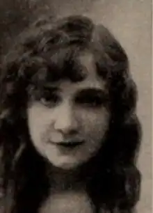 A young white woman with long loose wavy dark hair, in a side part. She has a dimpled chin.