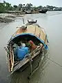 Bangladeshi fisherman resting in the shade of a sampan in Barishal