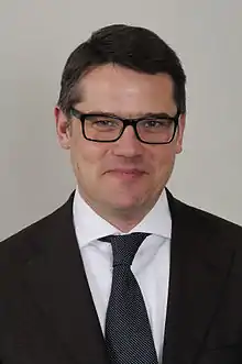 Portrait of a middle-aged white man wearing a dark suit and glasses