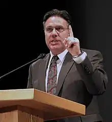 Man in a suit and tie speaking at a podium