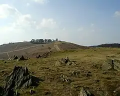 Picture of Old John Tower and the War memorial, at the top of the hill, above jagged rocks.