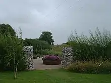 Shows an opening through a stone wall, looking into the autumn gardens, focusing on flowering "harvest basket".