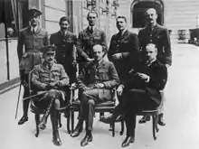 A black and white photograph of eight men, five standing and three seated, most of whom are wearing British military uniforms. The man standing in the middle is believed to be then-Lieutenant Colonel Pink.