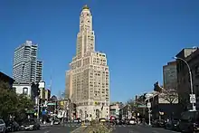 View of the Williamsburgh Savings Bank Tower from Fourth Avenue, several blocks south. Various low-rise buildings are located on either side of the avenue.