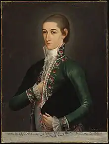 Portrait of a young man with his upper head shaved, wearing a green coat, white vest and holding a black hat with his left hand.