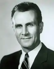 Black and white portrait photo of a middle-aged Caucasian man with short, somewhat receding hair and who is wearing a suit.