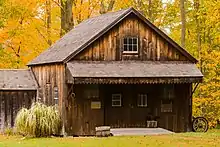 The front of the Brundage Blacksmith Shop, with yellow and green autumn leaves in the background