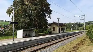 Yellow single-story building with gabled roof next to a single platform