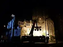 Six lights on a rig lighting up and in front of a Gothic Revival style church building.