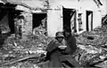 Soldier sitting for dinner in front of a ruined house