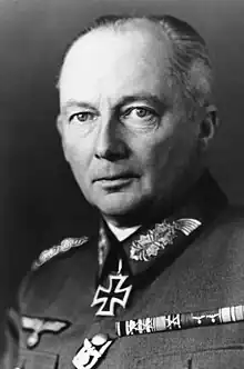 Black-and-white portrait of an older man wearing a military uniform with an Iron Cross displayed at his neck, his hair is combed back.