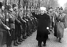 a male dressed in robes reviewing a parade of soldiers