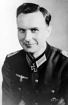 A black-and-white photograph of a smiling man wearing a military uniform and neck order in shape of an Iron Cross.