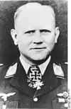 Black-and-white portrait of a man wearing a military uniform with various military decoration displayed at his neck.