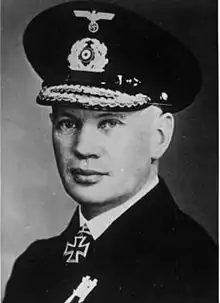 A man wearing a peaked cap and black naval uniform with an Iron Cross displayed at his neck.