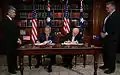 George W. Bush and John Howard signing a treaty inside the Commonwealth Parliament Offices.