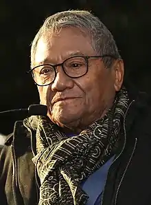 A man wearing glasses, a black jacket and a scarf.