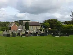 Grassy area with gravestones and grey-rendered chapel beyond