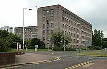 Six-storey office building made with prefabricated concrete panels and glass set in mature landscape