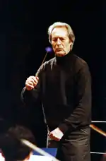 Giulini waving a baton to lead musicians.