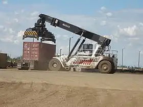 Reach stacker loading a box from freight train to truck