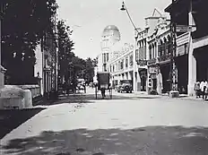  Photograph of a horse and cart on a road with an old ornate building in the background