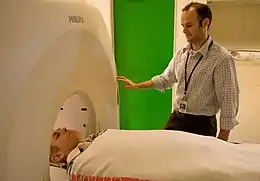 A man is lying on his back, about to go inside a cylindrical chamber.