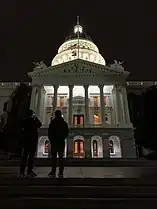 California State Capital at night with flags at half mast