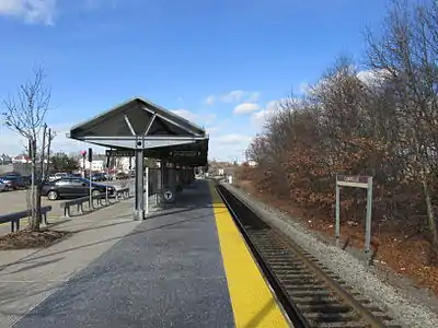 A concrete high-level station platform next to a single track