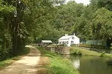 canal and towpath with lock house and concession stand in distance and woods in background