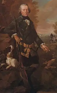 Painting shows a man in a dark coat holding a rifle and gesturing toward a dead rabbit. The man's dog looks on in this hunting scene.