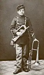 photograph of young Nielsen in band parade uniform with two brass instruments