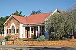 Single storey stone Arts & Crafts style building with white plaster decoration to windows and corners.
Doric columns to porch between two forward facing wings with triangular barge-boarded gable.
Architectural style: Arts & crafts.
Type of site: Library.
Current use: Library.