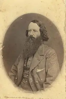 Sepia-toned photo of a heavily bearded man wearing a civilian coat and vest.