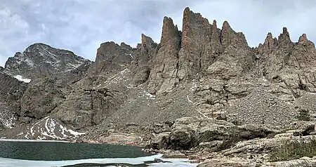 Cathedral Spires seen from Sky Pond. The apparent highest spire is "Saber" and immediately left of it is "Petit Grepon". At far left edge is Taylor Peak. Even though Sharkstooth is higher, it is hidden behind Saber.